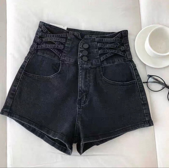 Black denim shorts on a white surface with a cup and glasses in the background