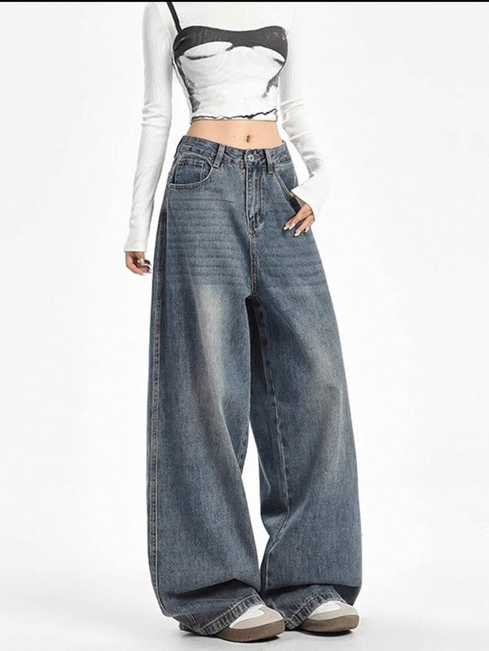 Person wearing a white long-sleeve crop top, black and white patterned crop top, and wide-leg blue jeans on a white background.