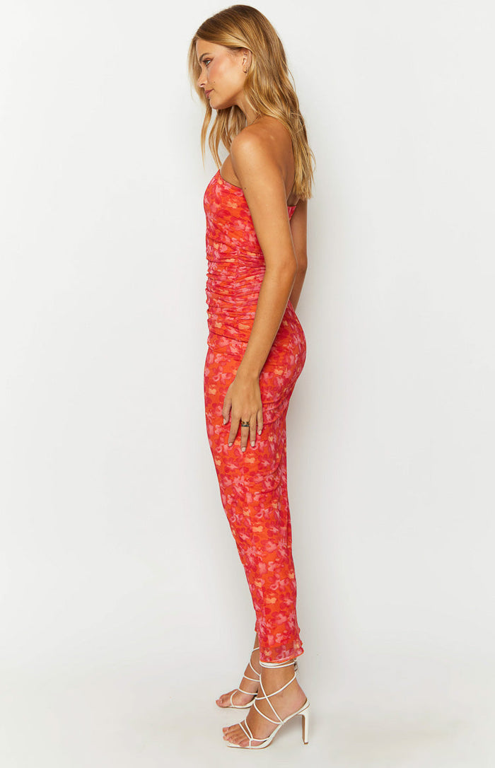 Side view of an orange floral print maxi dress with ruched side seams and spaghetti straps