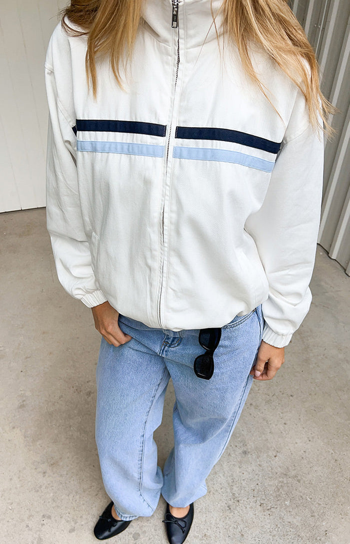 Cream funnel neck jacket with full zip front, navy and light blue chest stripes, elasticated cuffs and hem