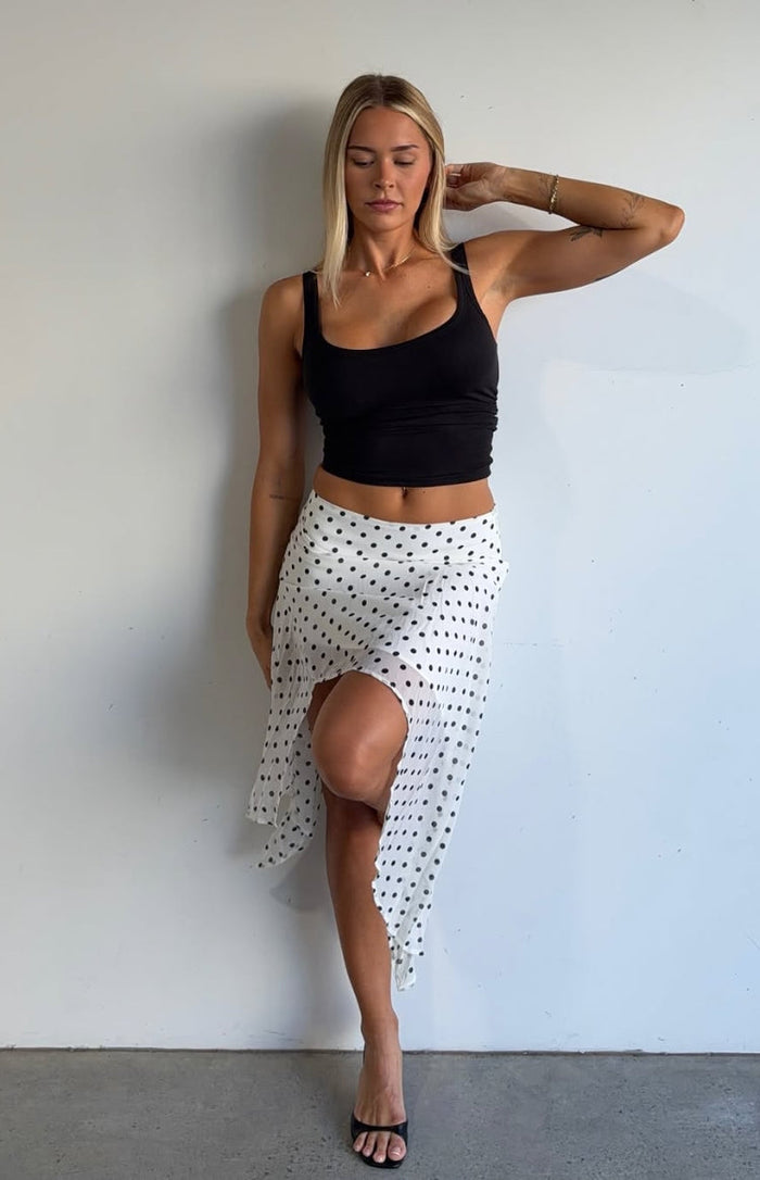 White polka dot midi skirt with a flowy hanky hem and a high leg slit