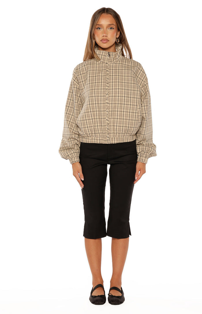 Front view of a beige plaid funnel neck jacket with a ruffled zipper and elasticated hem and cuffs