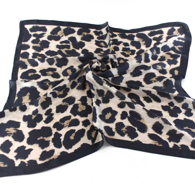 Square scarf with black leopard spots on a warm cream background and a solid black border.