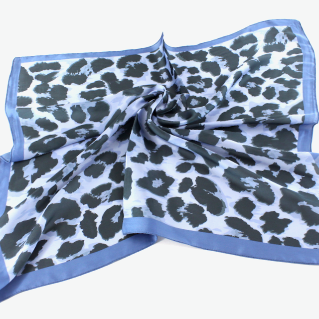 Pale blue square scarf with dark leopard spots and a contrasting deeper blue border.