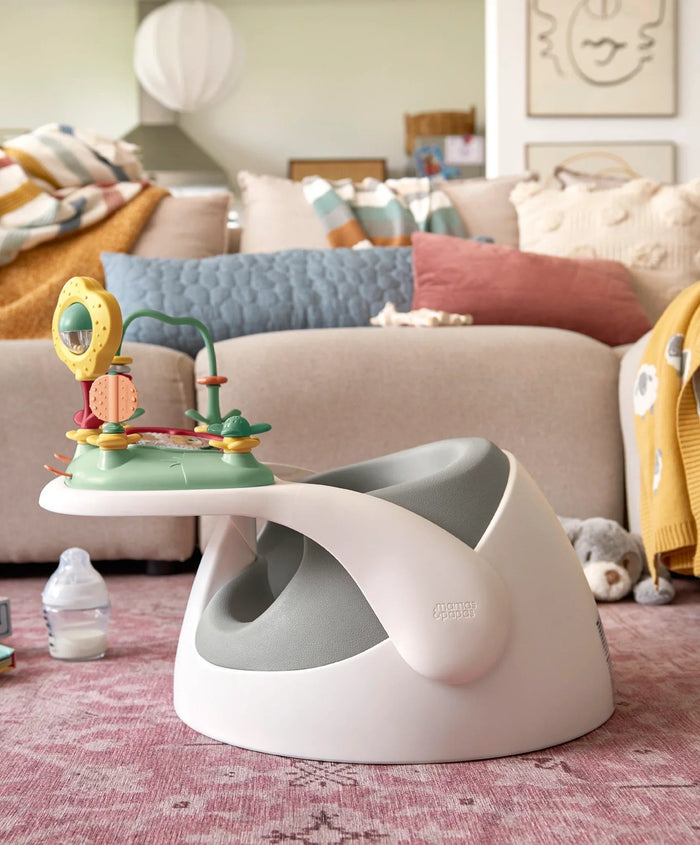 White and gray baby seat with activity center in Mamas & Papas Snug Floor Seat Pebble Grey, perfect for tiny explorers