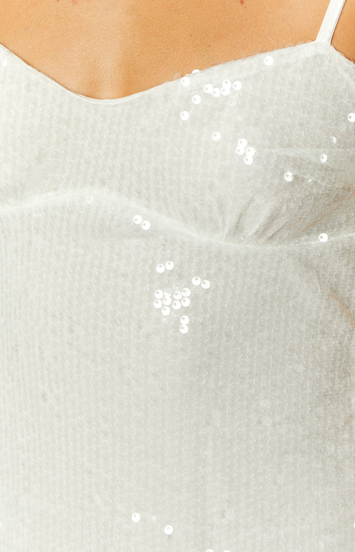 Close-up of the white sequin fabric on the bust of the mini dress, showing the delicate mesh base and ruched detail
