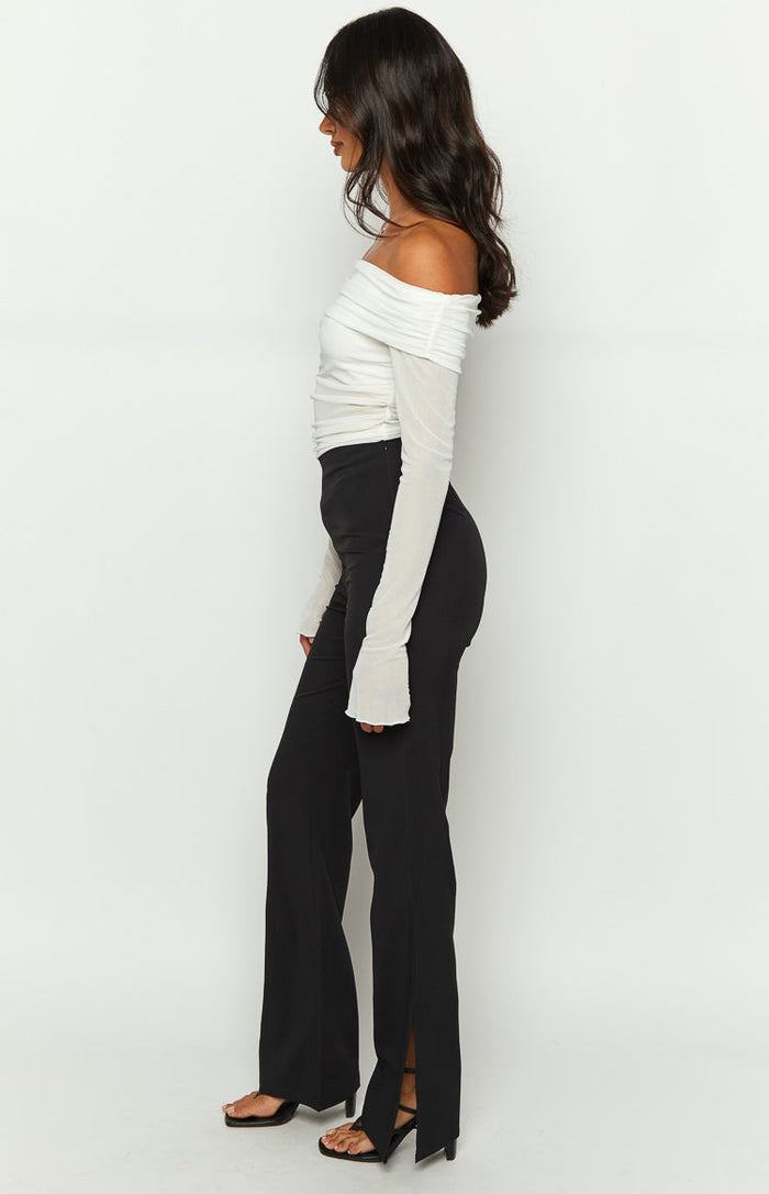 Side view of black pants showing the straight leg and long slit detail at the outer hem