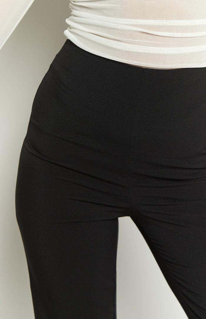 Black high-waisted straight leg pants with a subtle ankle slit