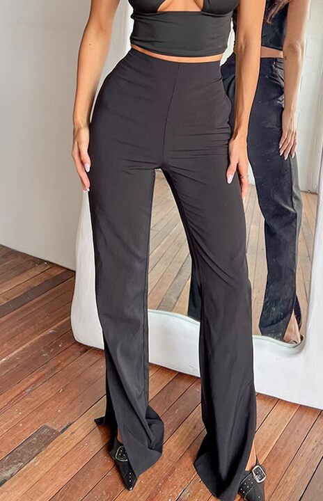 Rear view of black high-waisted pants with a fitted silhouette, slight flare, and ankle splits