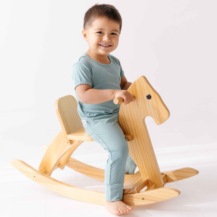 Child riding a wooden rocking horse on a white background