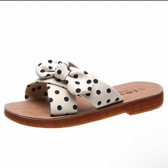White sandal with black polka dots and a bow on a white background