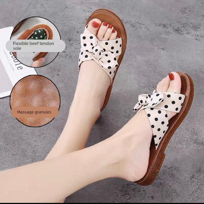 Polka dot sandals with a bow on a gray surface, showing sole details.