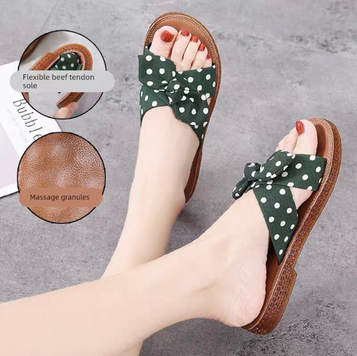 Green polka dot sandals with a brown sole on a gray surface, showing flexible beef tendon sole and massage granules details.