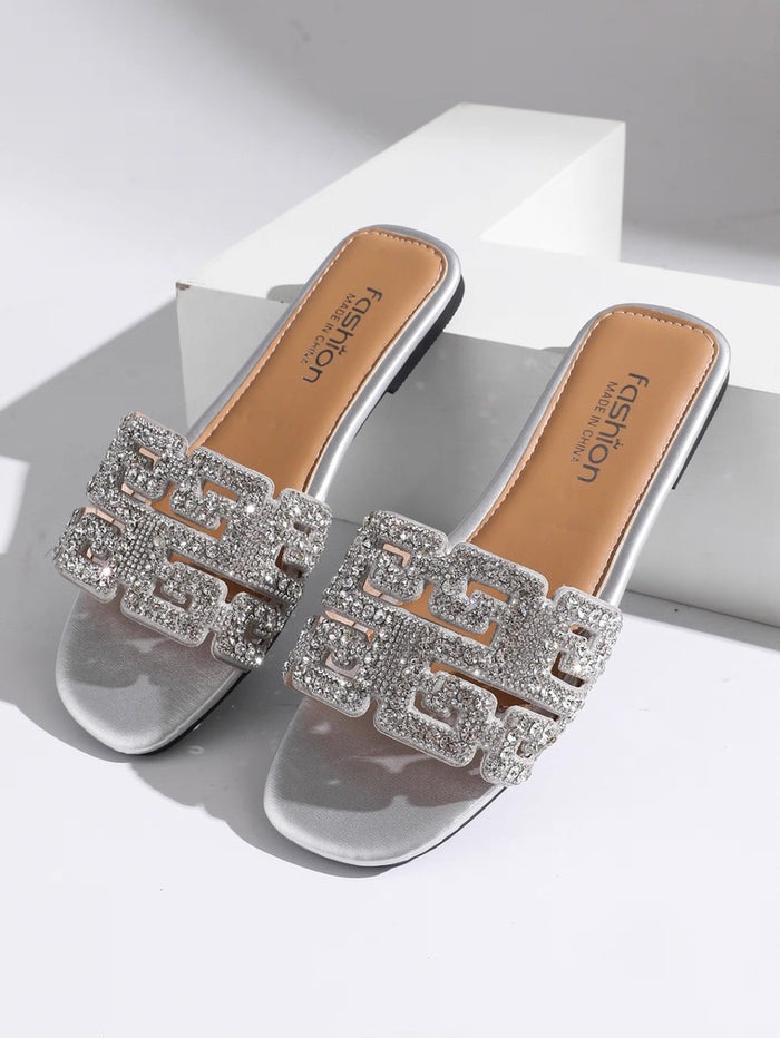 Silver embellished slide sandals on a white background