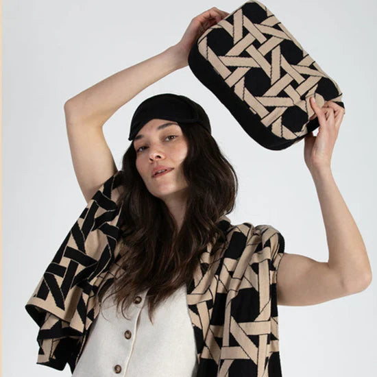 Woman holding a geometric-patterned bag and scarf against a white background