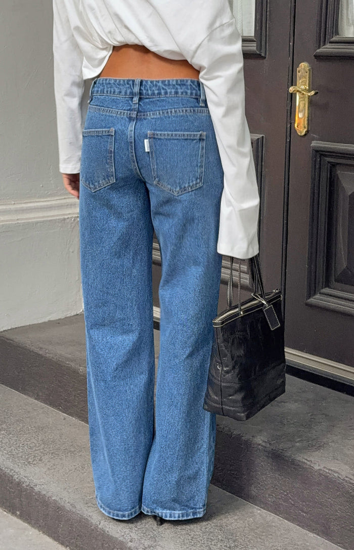 Rear view of mid wash denim jeans with back pockets and a relaxed wide-leg fit