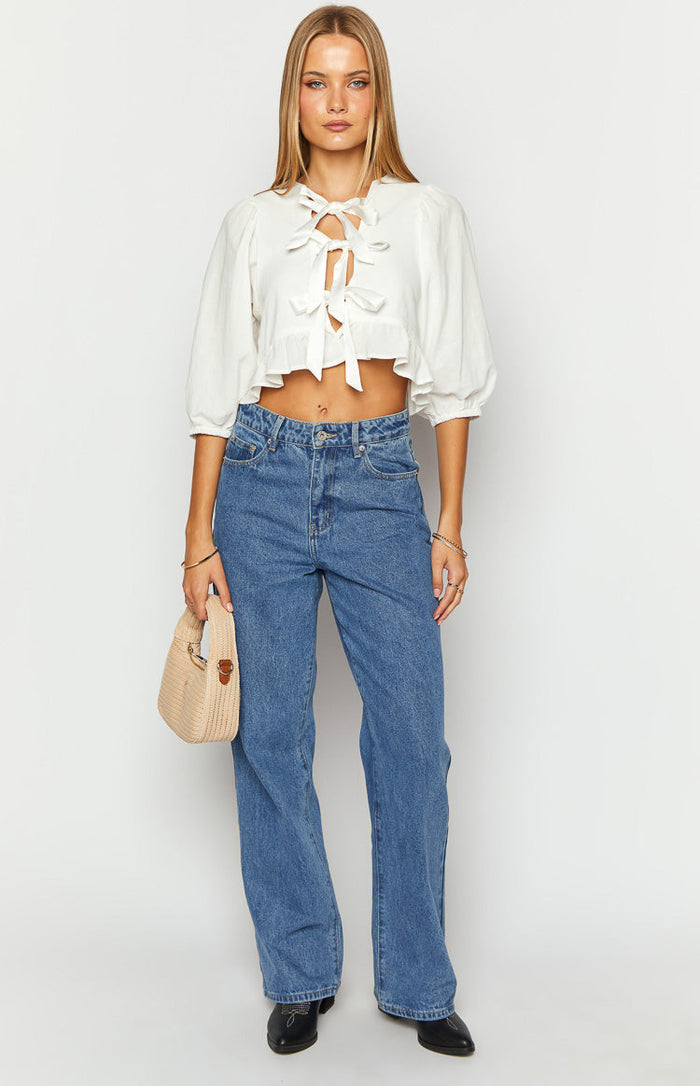 White tie up top with a V-neck, multiple front ties, half puff sleeves, and a ruffled cropped hem
