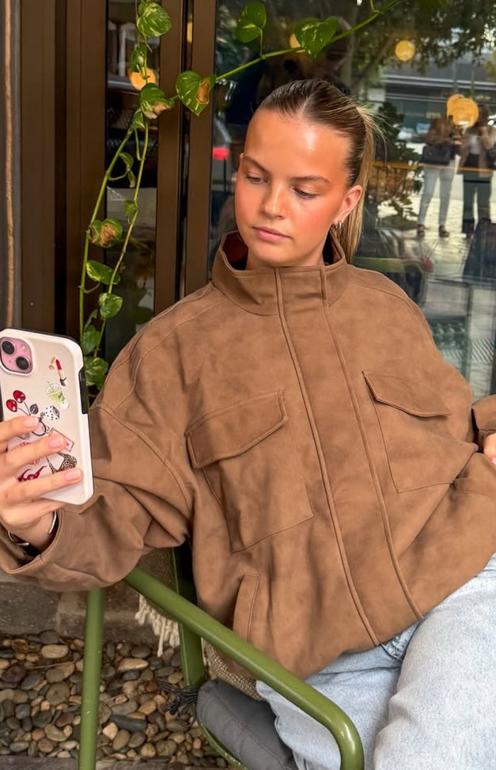 Close-up of a brown oversized suedette jacket with a funnel neck and two chest flap pockets