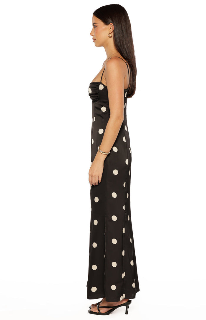 Side view of a black satin polka dot maxi dress with a ruched sweetheart neckline and thin straps
