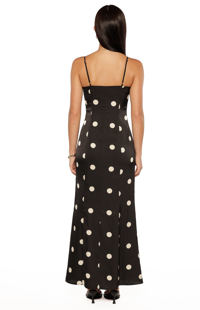 Rear view of a black satin maxi dress with white polka dots and thin spaghetti straps