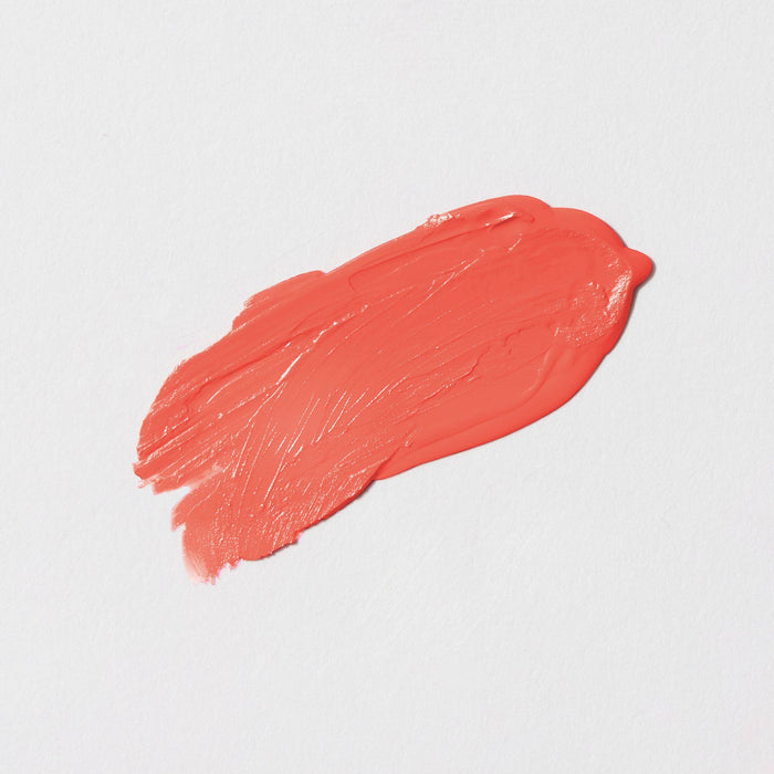 Smeared coral-colored lipstick on a light gray background