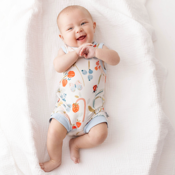 Baby wearing a floral onesie lying on a white blanket