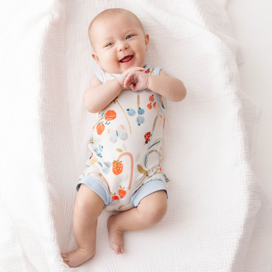 Baby wearing a floral onesie lying on a white blanket