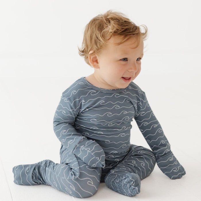 Child wearing a blue patterned onesie on a white background