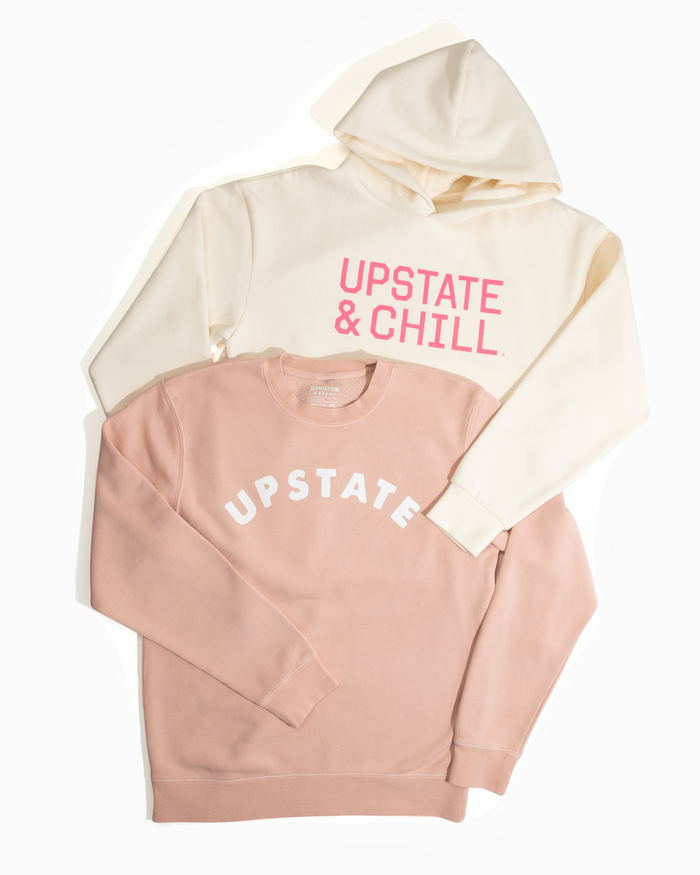 Two hoodies, one beige and one pink, with 'Upstate & Chill' text on a white background.