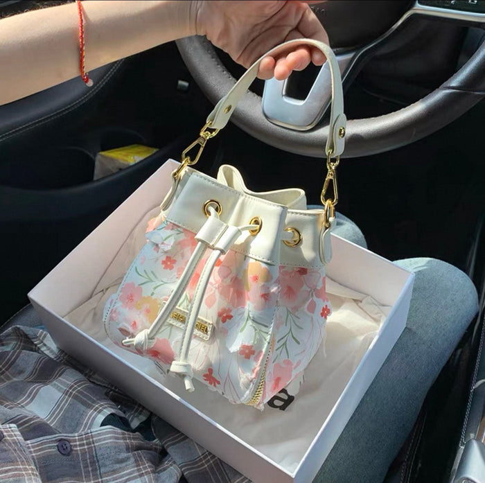 Floral-patterned handbag in a box held by a person inside a car.