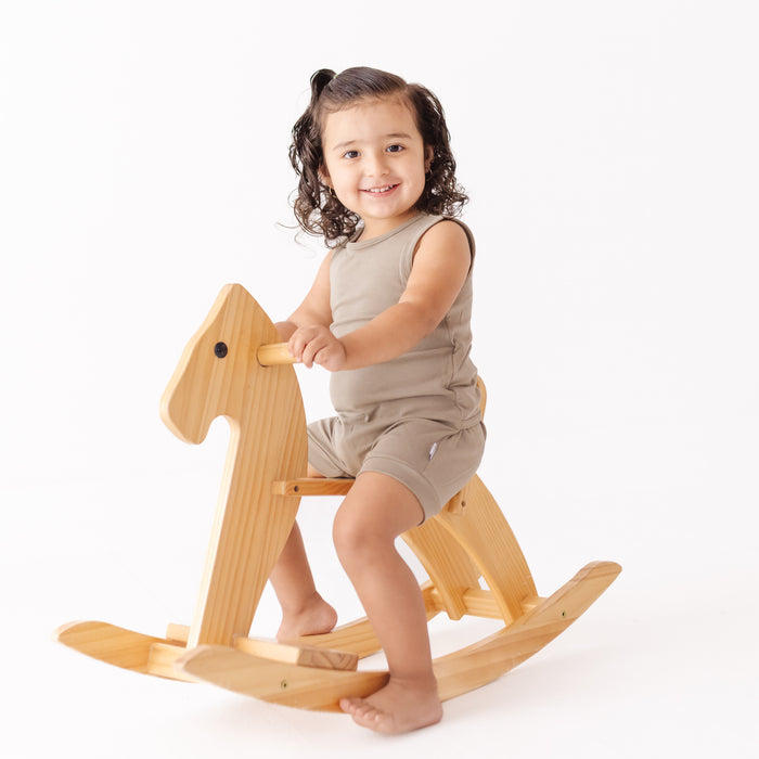 Child sitting on a wooden rocking horse against a white background