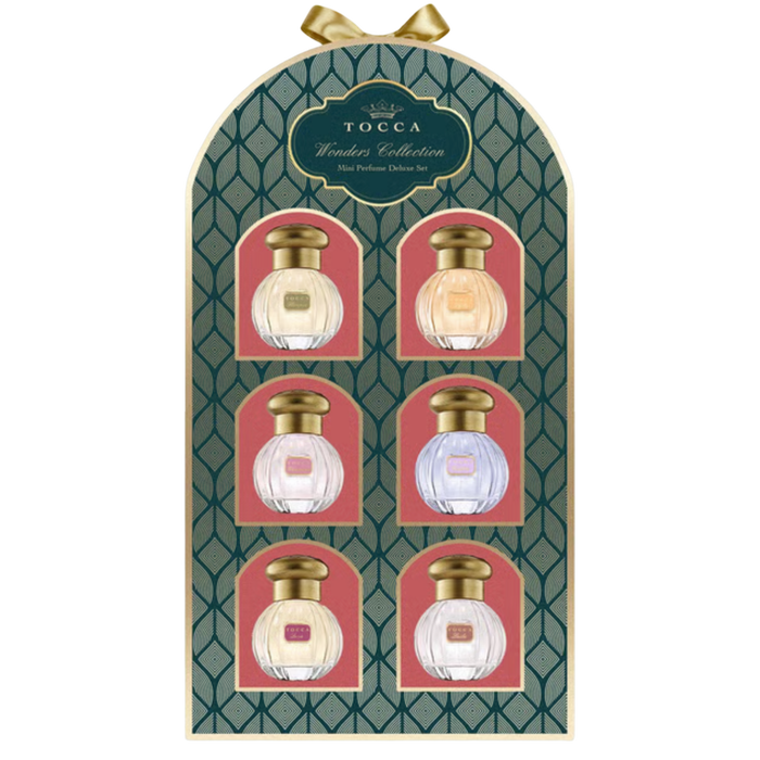 TOCCA Wonders Collection 6-piece perfume set in an arched gift box. The packaging features a dark green geometric pattern with gold trim, six pink arches, and six clear glass perfume bottles with gold caps, each bottle containing a different colored liquid.