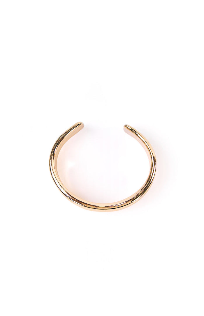 Overhead view of a shiny gold wavy cuff bangle, highlighting its open C-shape and polished finish