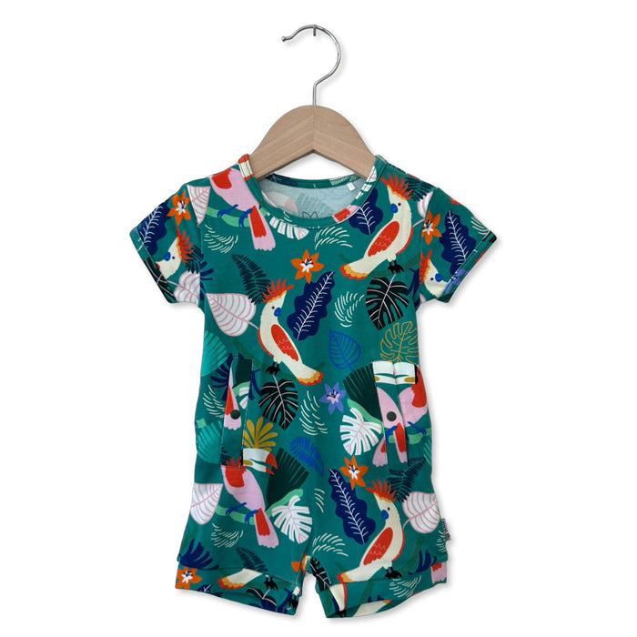 Children's outfit with tropical bird and leaf pattern on a hanger against a white background