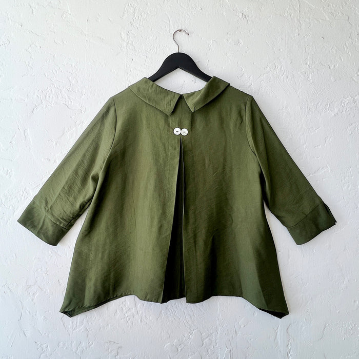 Green coat on a hanger against a white wall