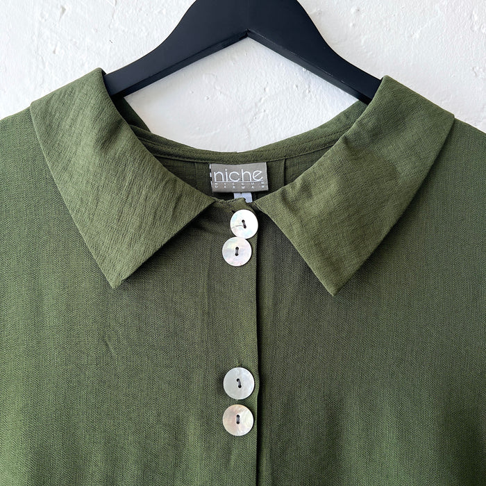 Green shirt with collar and buttons on a hanger, featuring 'niche' brand label.