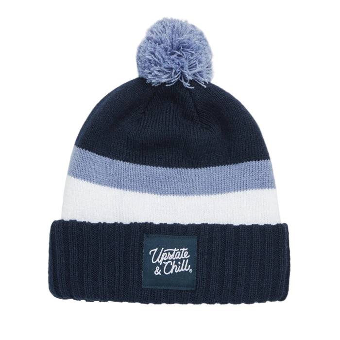 Navy blue, white, and gray striped beanie with pom-pom on a gray background