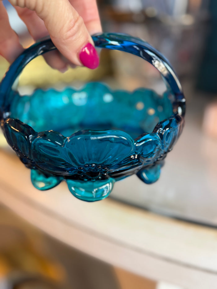 Blue glass bowl held by a hand with pink nail polish.