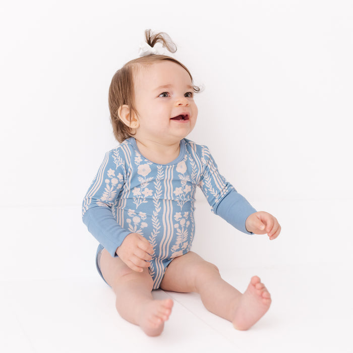 Baby wearing a blue floral onesie on a white background