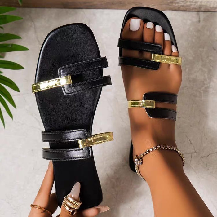 Black sandals with gold buckles on a neutral background