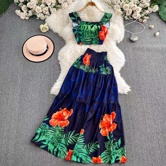 Navy blue dress with red floral pattern on a gray surface with flowers and a hat.