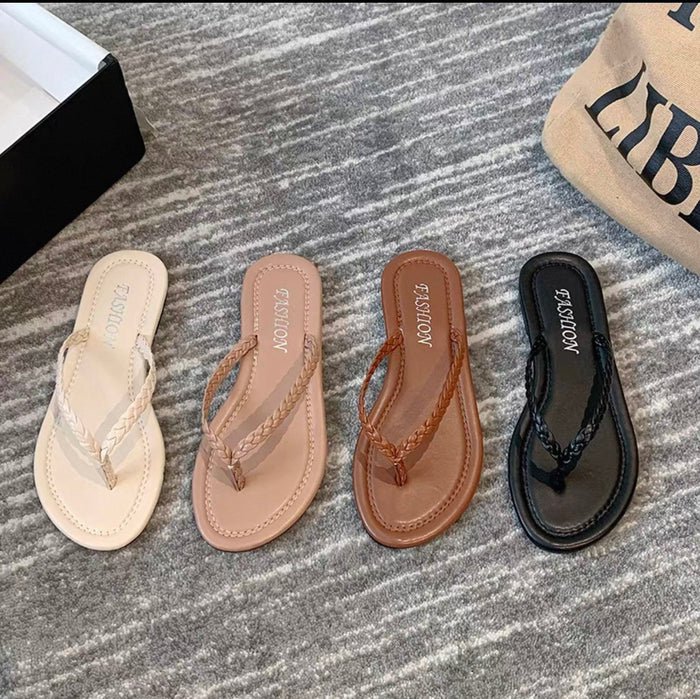 Four pairs of sandals in different colors on a textured surface.