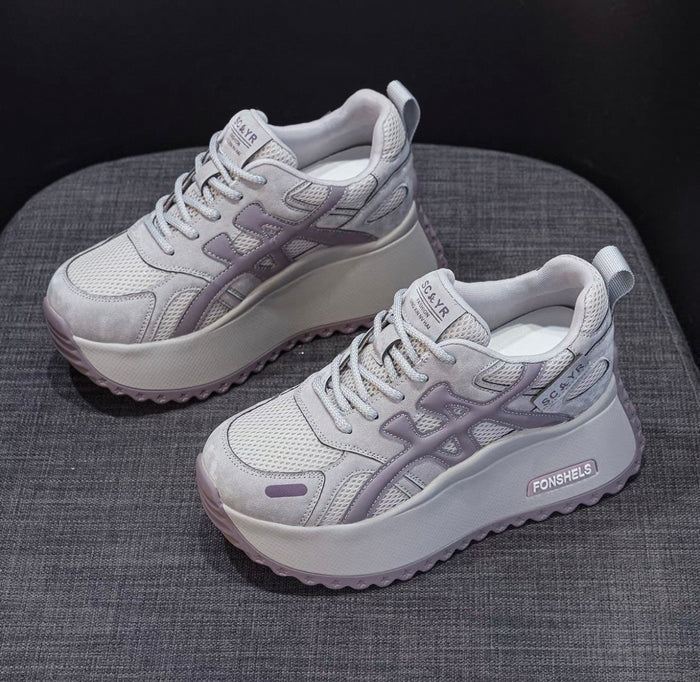 Pair of gray sneakers on a textured surface with a dark background