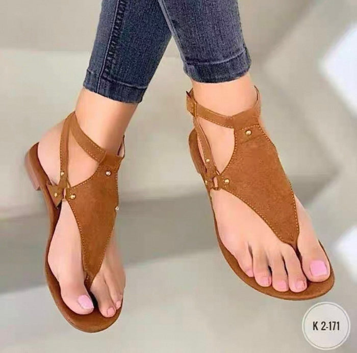 Brown sandals worn with rolled-up jeans on a neutral background