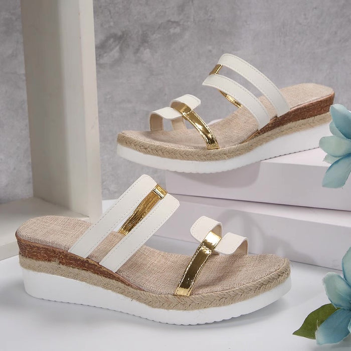 Pair of sandals with white straps and gold accents on a neutral background