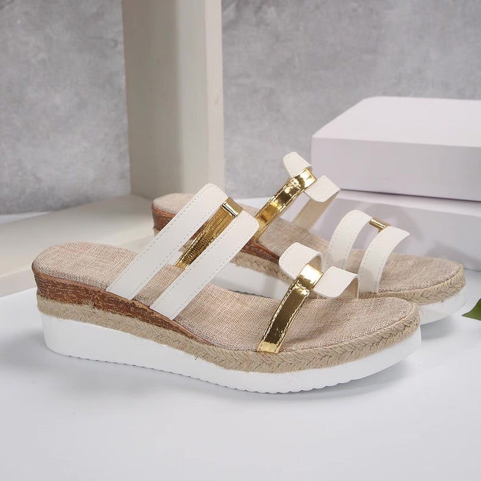 Beige sandals with white straps and gold accents on a light gray background