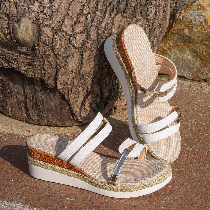 Beige and white wedge sandals with jute details on a stone surface.