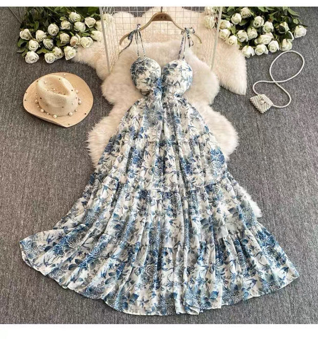 Floral dress on a hanger with a hat, bag, and flowers on a textured surface