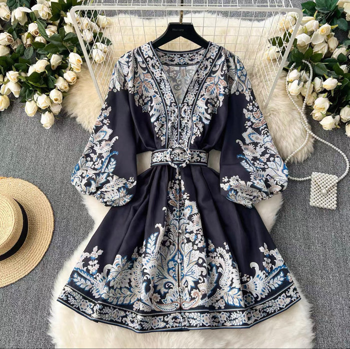 Navy blue dress with white floral pattern on a gray surface with decorative elements.