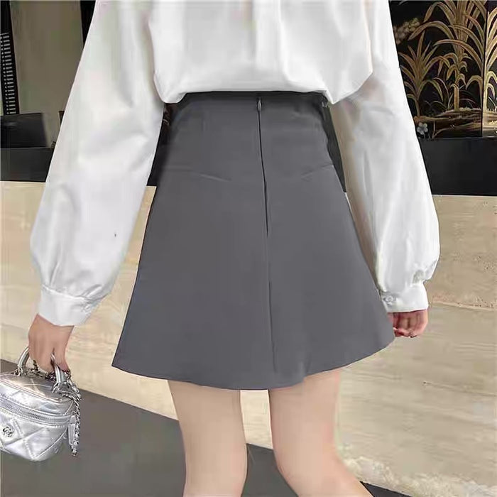 Person wearing a white blouse and gray skirt with a blurred background